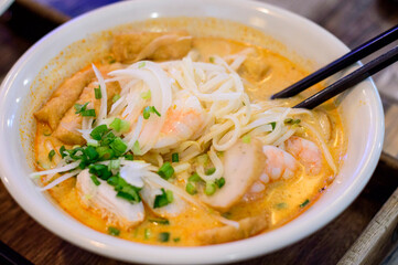 Top view of Vietnamese pho with prawns, chicken and tofu on top.