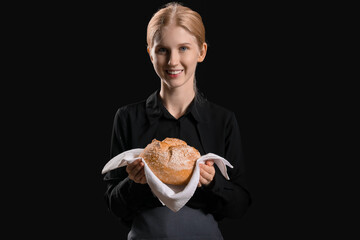 Young woman holding napkin with fresh bread on black background