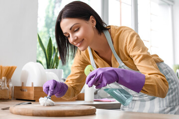 Young woman cleaning cutting board with brush in kitchen