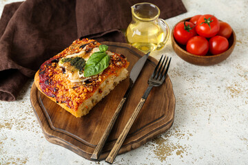 Wooden board with piece of tasty Italian pie and cutlery on light background