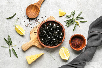 Composition with plate of tasty black olives, spices and lemon on light background