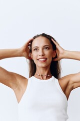 Portrait of a beautiful woman with tanned skin and a beautiful snow-white smile and brown natural long hair on her head posing against a white background touching her hair. Care of her long hair