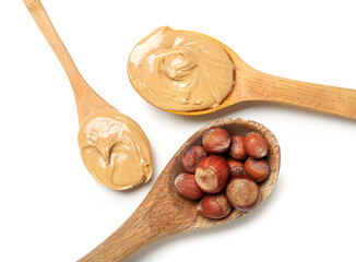 Wooden spoons with tasty hazelnut butter and nuts on white background, closeup