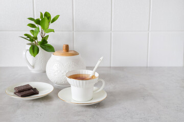 white porcelain cup with tea and chocolate on the table