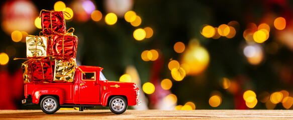 Banner photo of red small retro toy truck with christmas gifts on background of Christmas tree...
