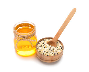 Bowl of sesame seeds and jar with oil on white background