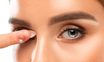Beautiful blue eyed young woman holding a contact lens on her finger. Eye care and choice of means...