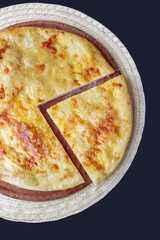 Traditional Georgian dish - khachapuri on a wooden board and a dark table. Top View