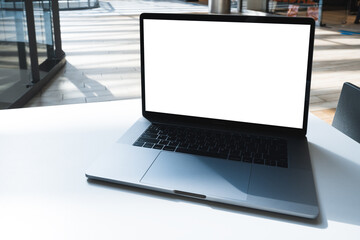 Laptop mockup with white screen in business office or shopping mall. Empty copy space, blank screen mockup. Soft focus laptop with interor background. Travel, study and office work concept