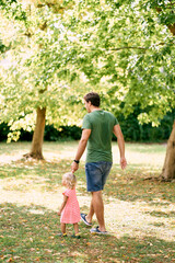 Dad and little girl walk through the woods holding hands. High quality photo