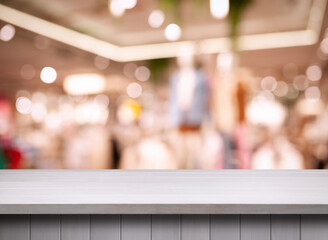 Empty white wooden surface and blurred view of clothes store interior. Space for design