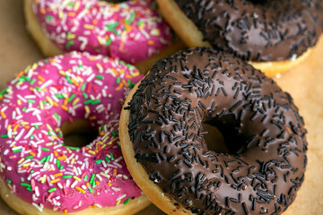 Delicious chocolate and strawberry glazed donuts with sprinkles close up image