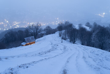 Evening winter landscape with a road and a lonely wooden house