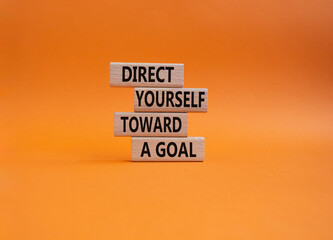Direct yourself toward a goal symbol. Wooden blocks with words Direct yourself toward a goal. Beautiful orange background. Business and Direct yourself toward a goal concept. Copy space.