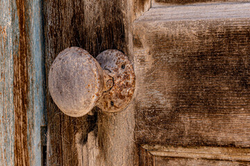 Rusty doorknob on faded wooden door