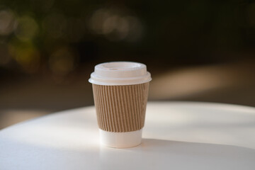 paper cup with a hot drink stands on a white table in a cafe