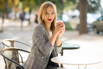Fototapeta na wymiar smiling girl in a business jacket, sitting in a cafe