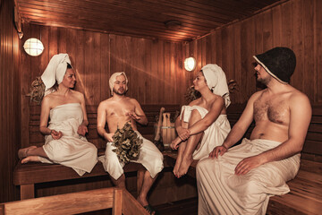 Russian bathhouse. Two couple relaxing and sweating in wooden sauna with hot steam. Four person...