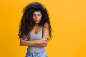 Offended upset angry millennial Latin woman with crossed hands on chest, isolated on yellow background, free space. Female emotions, human sad facial expression, copy space