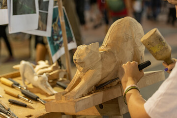 Hands of a wood sculptor working on a small wooden figure