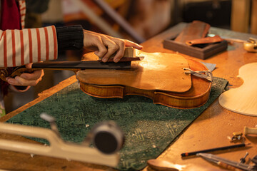 Close up of professional master artisan luthier working on creation of handmade violin in a workshop.