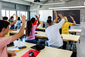 Fototapeta Group of high school students raising hands in classroom - Education concept obraz
