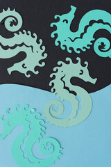 green paper seahorses on dark gray and blue paper