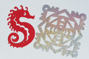 red paper seahorse and glitter foil snowflake on blank paper