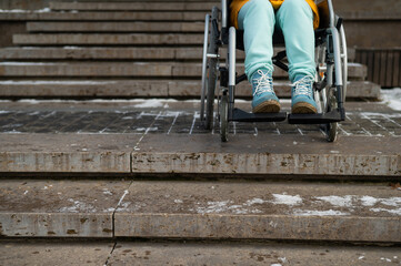 Woman in a wheelchair near the stairs in the park in winter.