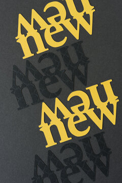 the word "new" (double or mirrored) in yellow and black card stock on dark gray board