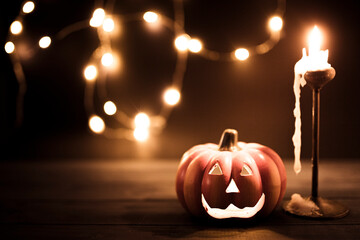 Halloween pumpkin wallpaper with candle and string lights bokeh in the background. Toned vintage...