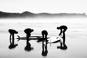 High contrast silhouette of surfer people carrying their surfboard on beach
