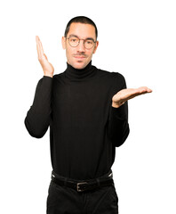 Fototapeta premium Doubtful young man holding something with his hand