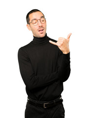 Amazed young man making a gesture of calling with the hand