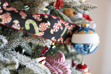 Close up of snow cover Christmas tree decorated for Christmas with ribbon, blue round ornament, and candy canes