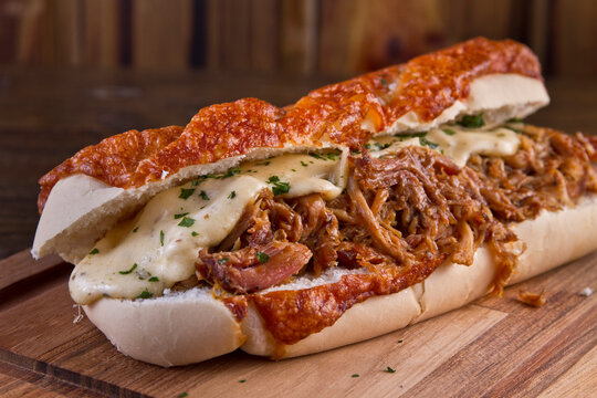 Lanche de frango desfiado com queijo derretido servido em tabua de amdeira
