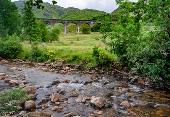 Glenfinnan Viaduct, met bomen en rotsachtige stroom op de voorgrond, Glenfinnan, Inverness-shire, Schotland, VK.