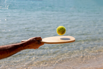 Hand with a racket ball close-up. A man on the beach with a racket. The rest of the game.