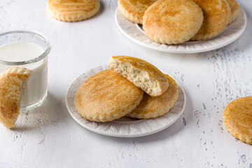 Sweet milk shortbreads with a glass of milk on a light blue background. Traditional Russian...