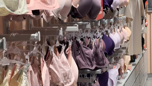 Women's bras and underpants hang on hangers in a lingerie store