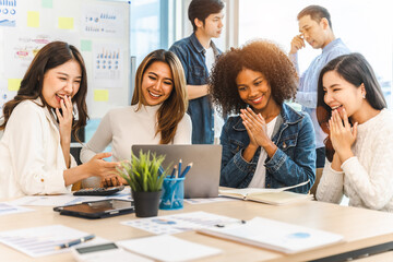 Young and successful mixed race, asian business people working on project together, sitting at table in boardroom.
