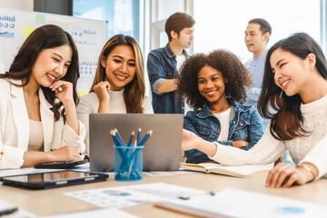 Young and successful mixed race, asian business people working on project together, sitting at table in boardroom.