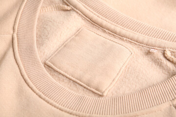 Blank clothing label on beige sweater, closeup