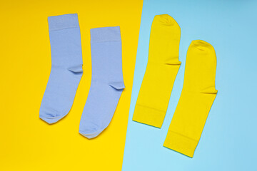 Blue and yellow socks on color background, flat lay