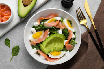 Delicious salad with boiled egg, salmon and avocado served on light grey marble table, flat lay