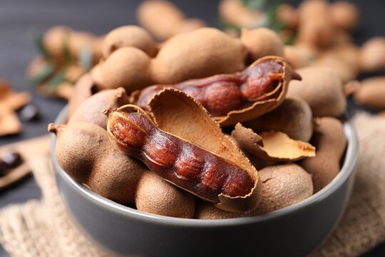 Delicious ripe tamarinds in ceramic bowl on table, closeup