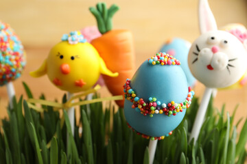 Delicious sweet cake pops in green grass, closeup. Easter holiday