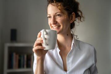Woman standing in the office with cup of coffee morning daily routine