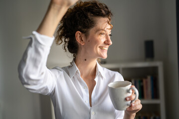 Woman standing in the office with cup of coffee morning daily routine