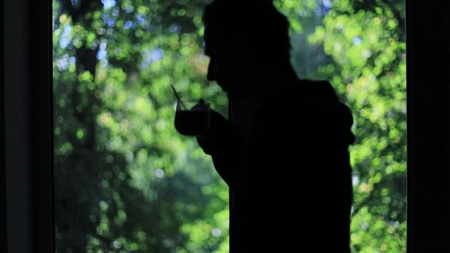 A guy smokes in front of a window. Bad habits of man. Abuse of nicotine. A strong addiction. Smoking, guy, window, silhouette, details, morning, light, summer, nicotine, cigarette, black, shadow, torm